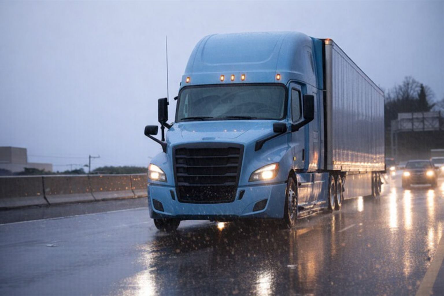 Sininen rekka-auto ajaa moottoritiellä voimakkaassa sateessa.