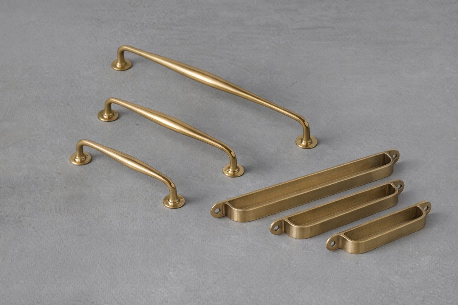 Eri kokoisia messinkisiä vetimiä ja kuppivetimiä harmaalla taustalla.